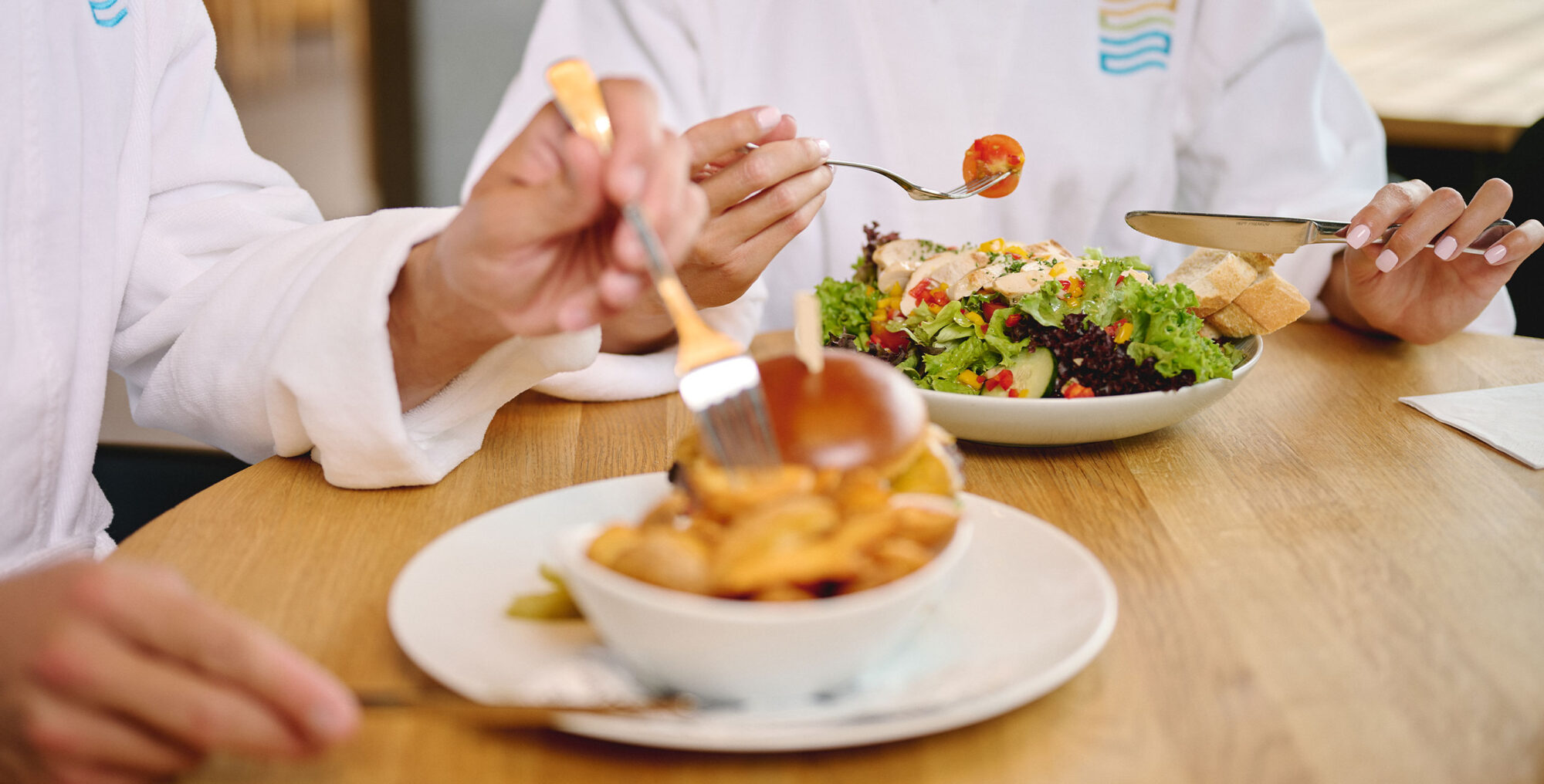 Nahaufnahme eines Burgers mit Pommes und eines Salates