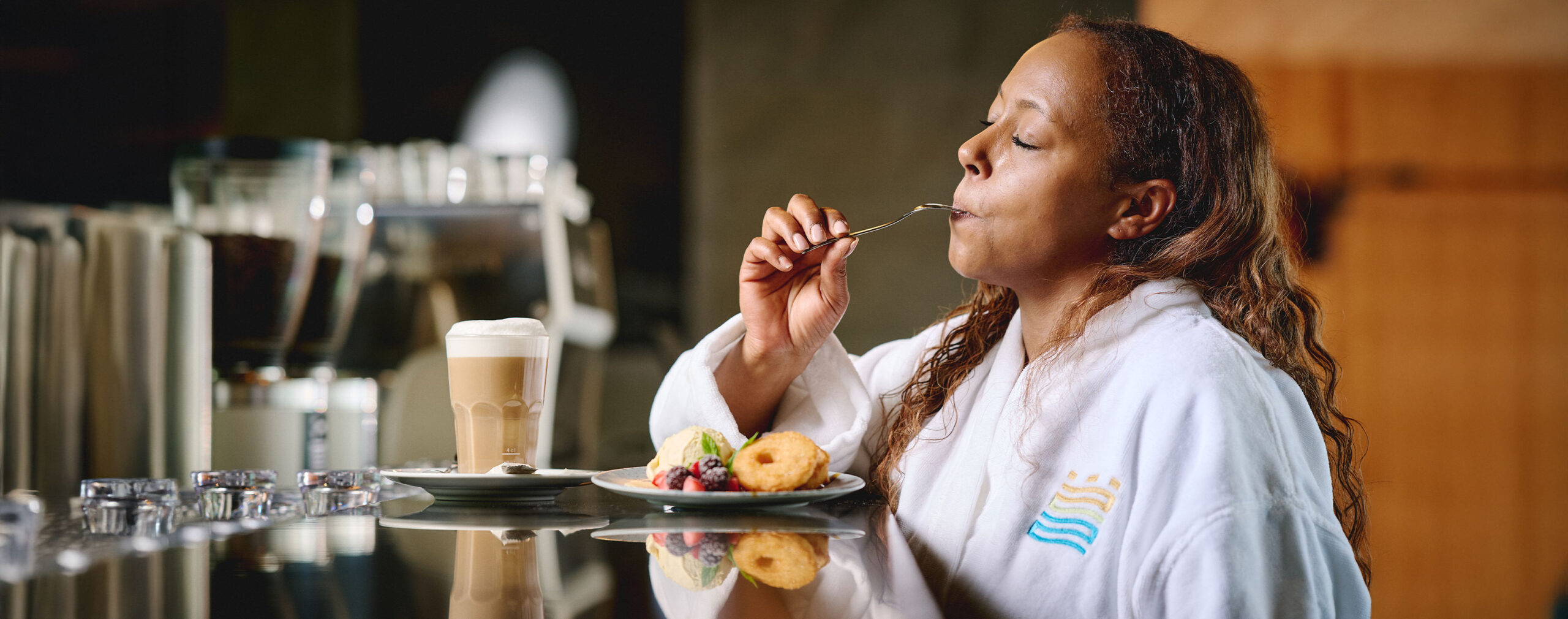 Frau genießt Latte Macchiato und Apfelküchle in der Sauna-Gastro