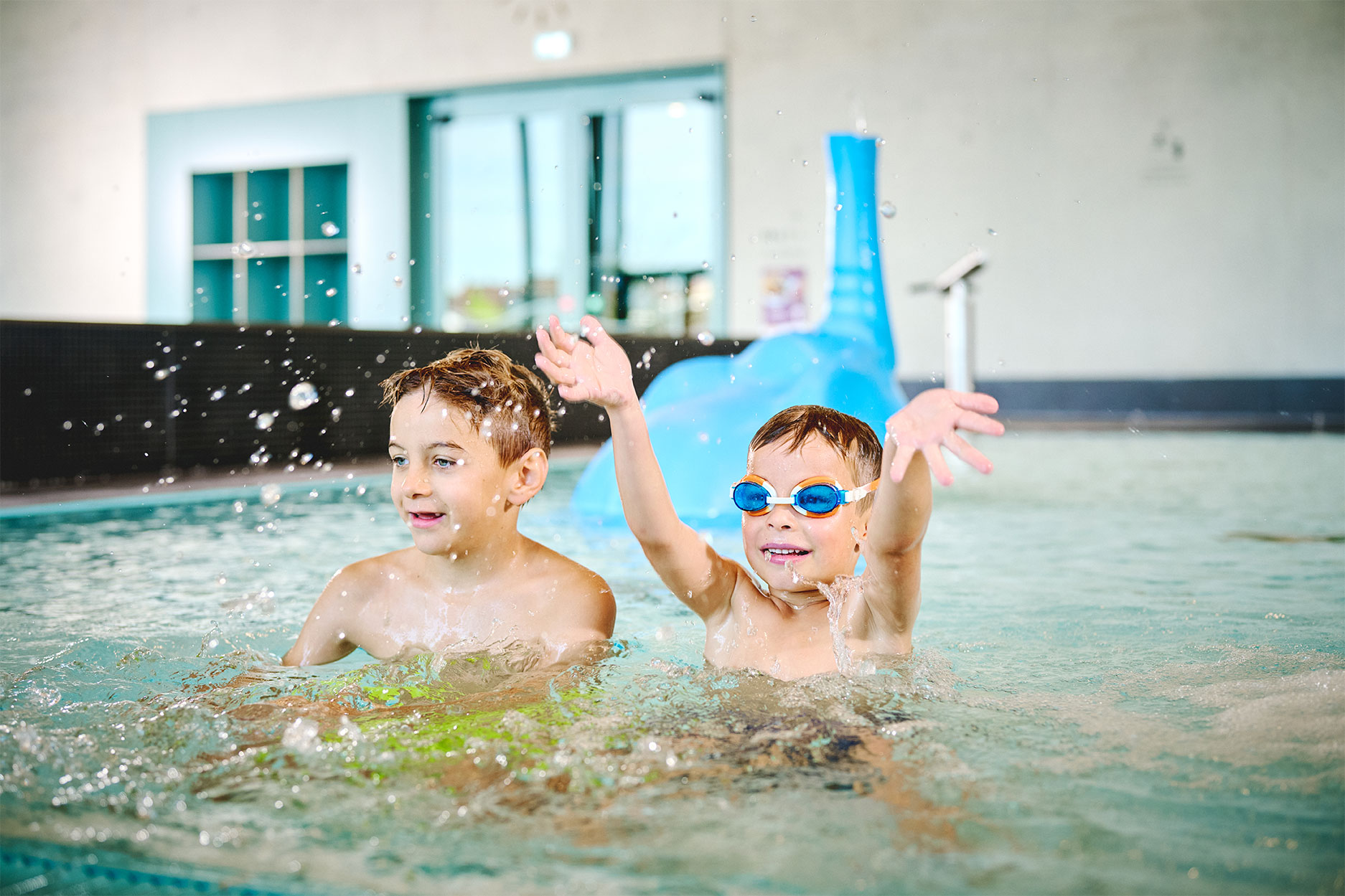 zwei Jungen spielen im Kinderbecken und spritzen mit Wasser