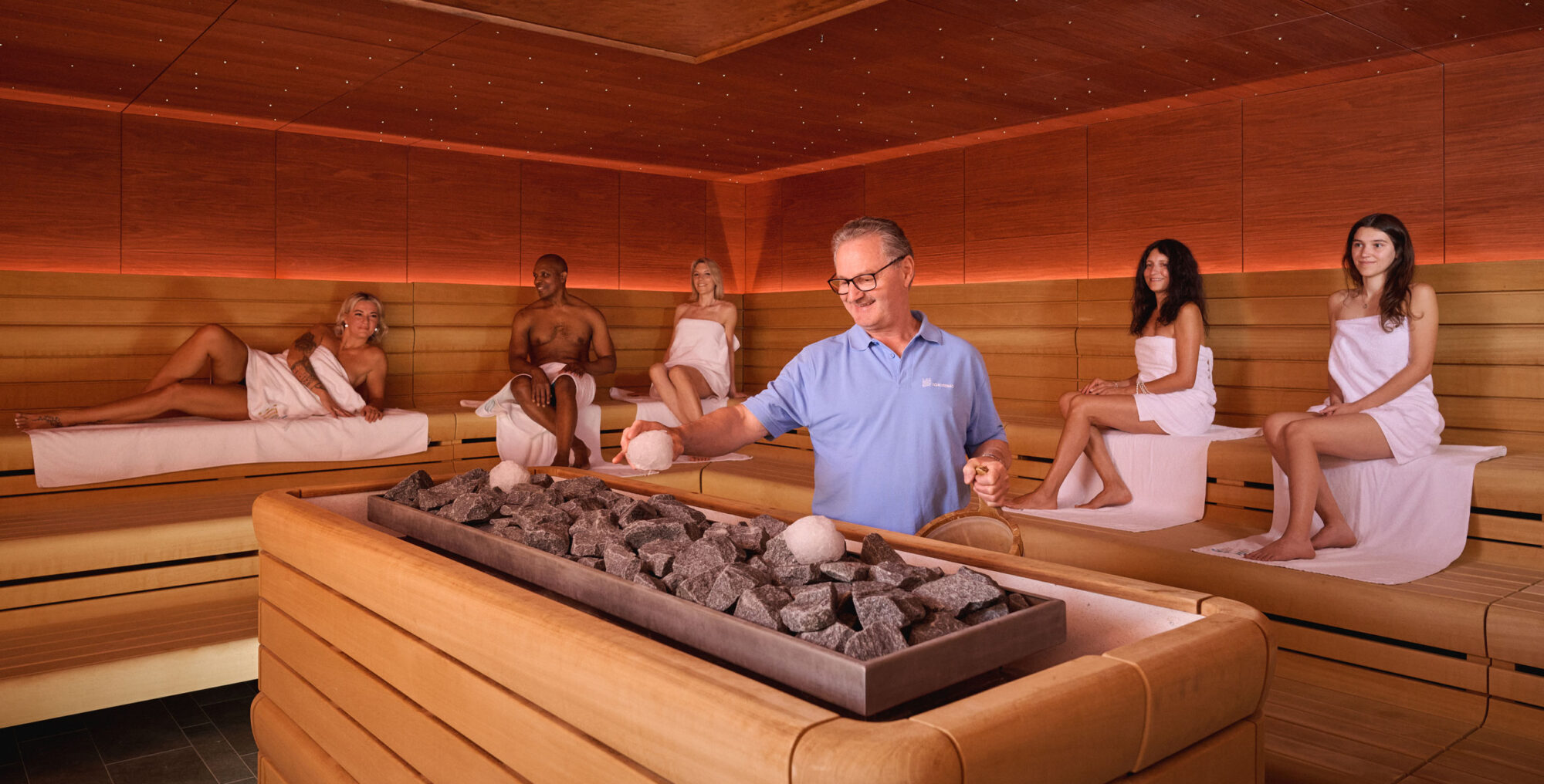 Saunameister legt Eisball auf den Saunaofen in der Pfalzgrafensauna