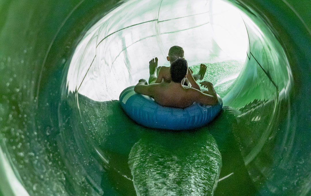 Vater rutscht mit Kind in der Reifenrutsche auf blauem Reifen