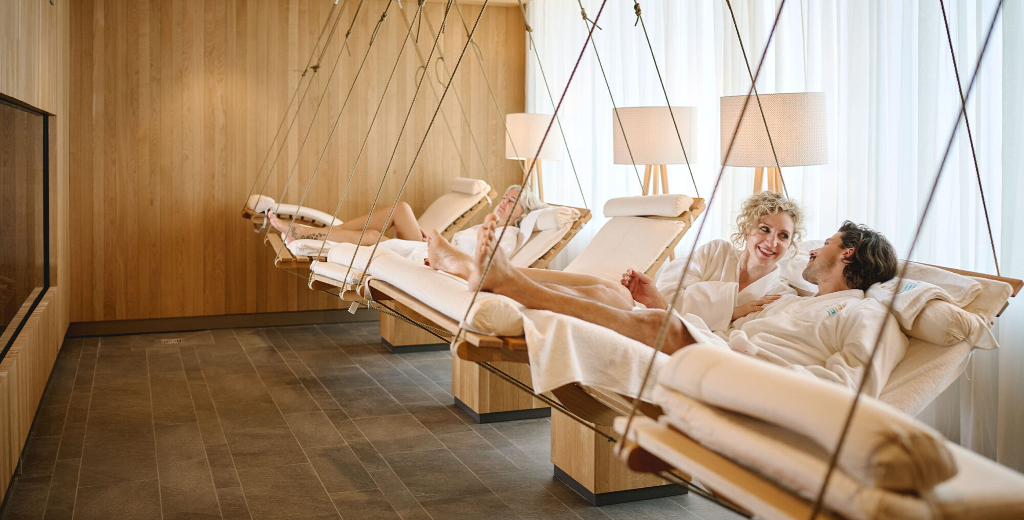 Paar liegt im Bademantel auf Schaukelliegen